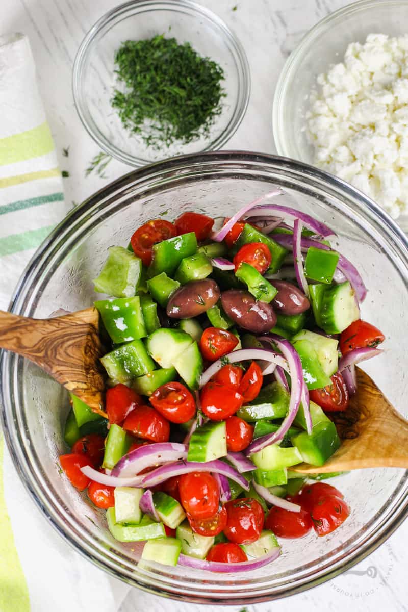 mixing dressing and Greek Salad ingredients