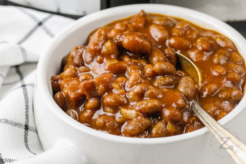 close up of Easy Slow Cooker Baked Beans in a white bowl with a spoon