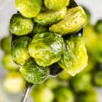 Instant Pot Brussels Sprouts on a spoon with bowl full in the back