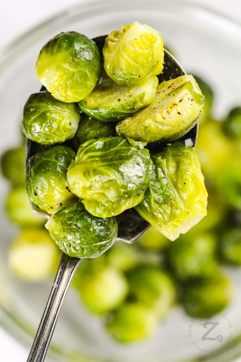 Instant Pot Brussels Sprouts on a spoon with bowl full in the back