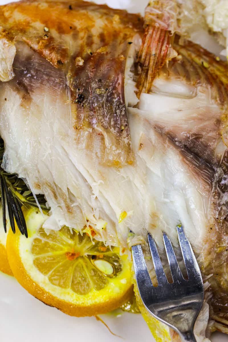 fork taking a part from a Baked Whole Fish