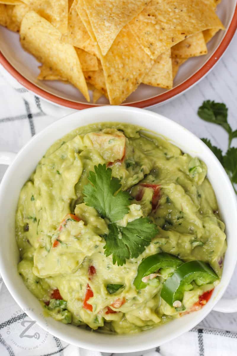 top view of Guacamole with Tomatoes in a bowl with chips