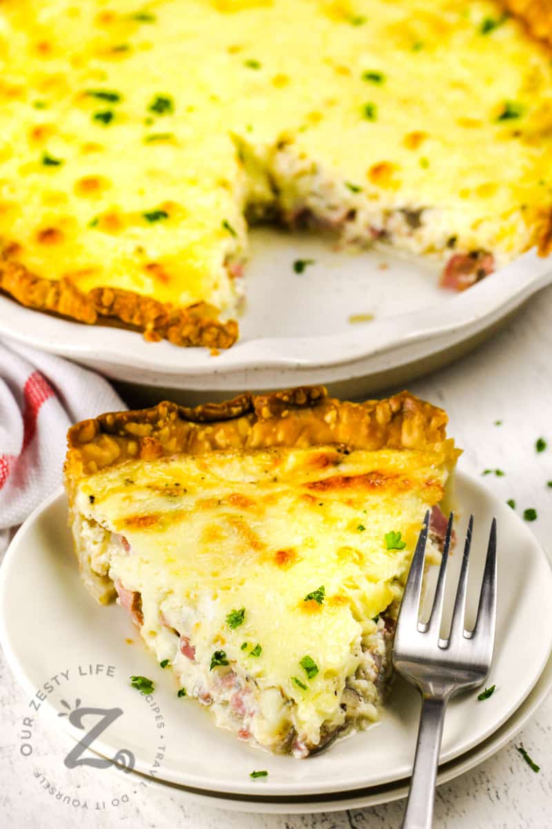 piece of Quiche with Ham on a plate with the quiche in the back