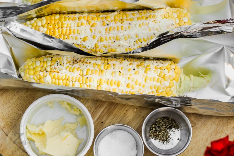 adding sauce and spices to corn to make Grilled Corn in Foil