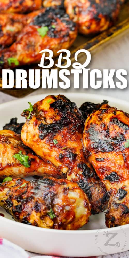 BBQ Drumsticks on a plate with baking sheet full and a title