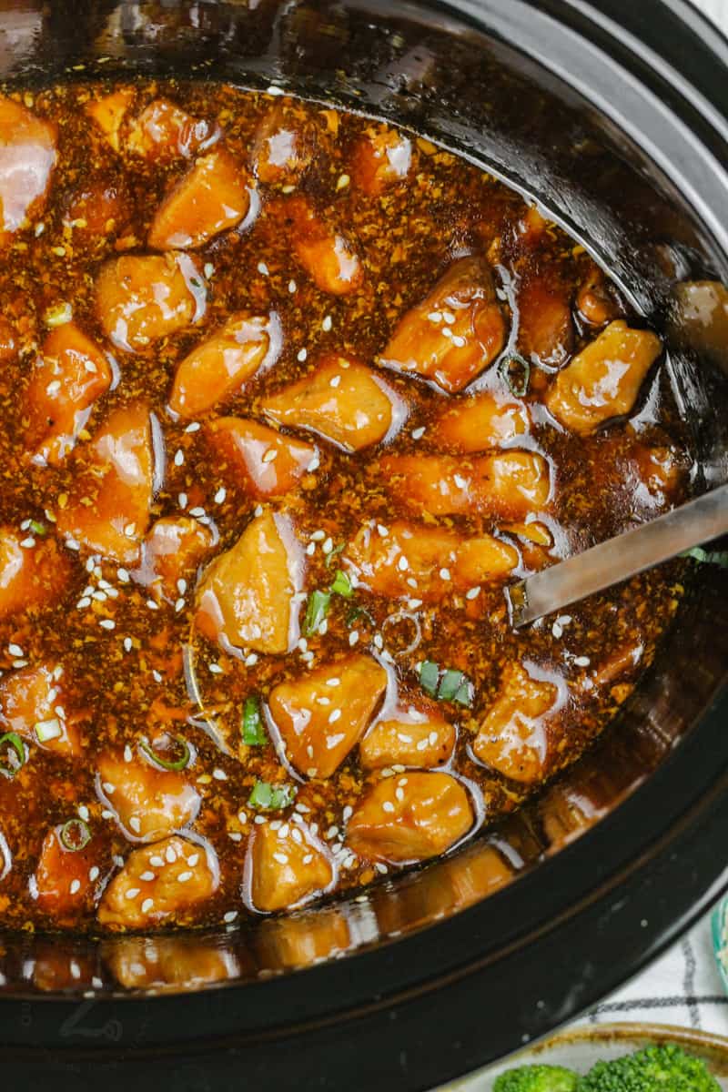 cooked Slow Cooker Honey Garlic Chicken in the crockpot with a spoon