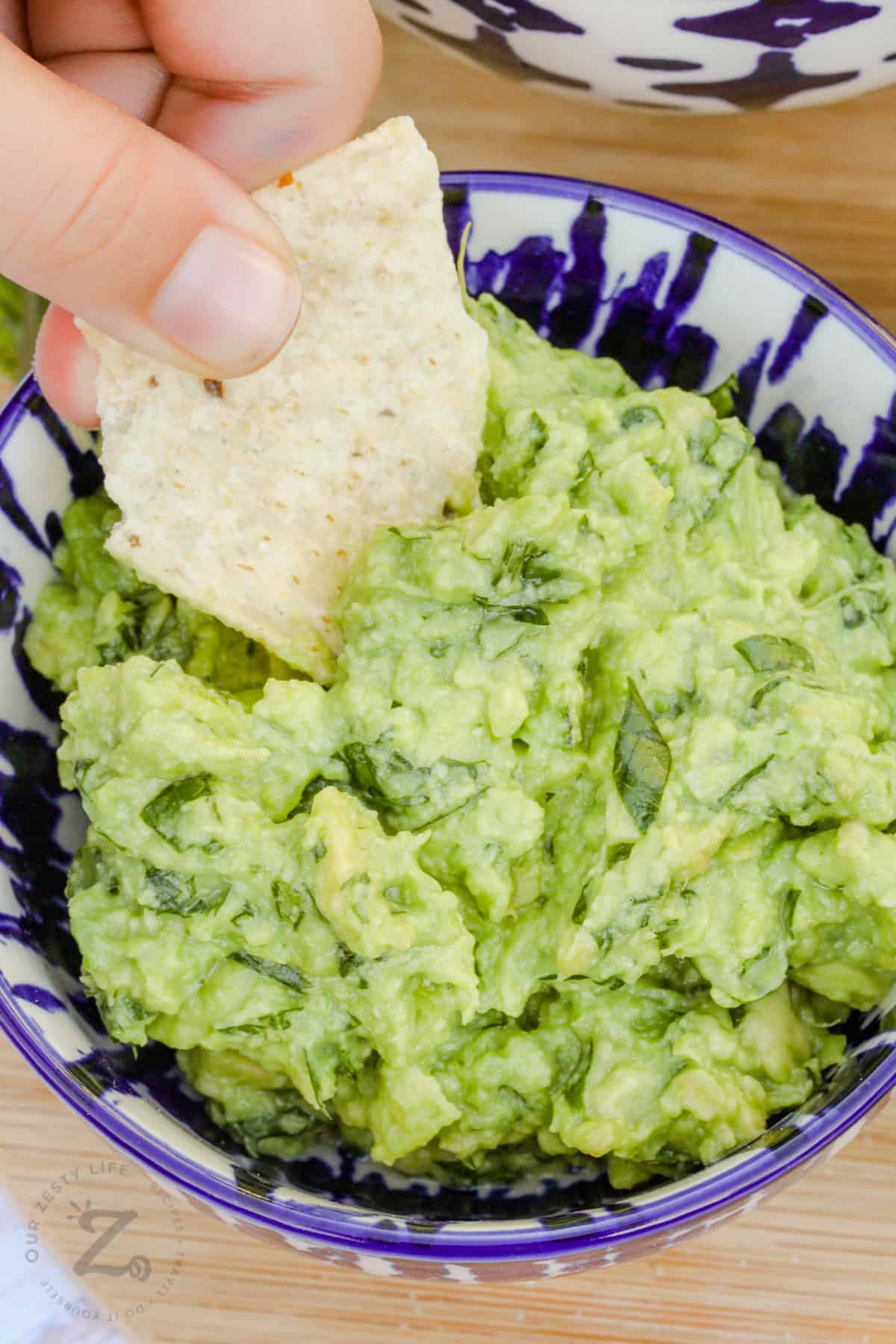 dipping a chip in Easy Homemade Guacamole