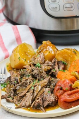 Instant Pot Pot Roast on a plate with instant pot in the background
