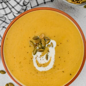 top view of bowl of Pumpkin Soup and bowl of seeds