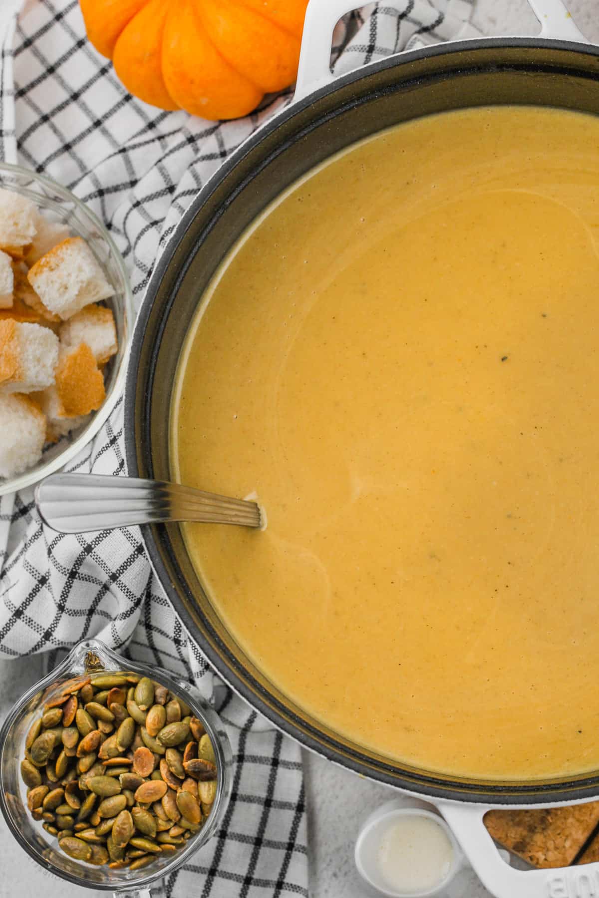 Pumpkin Soup in a bowl with bowls of ingredients around it