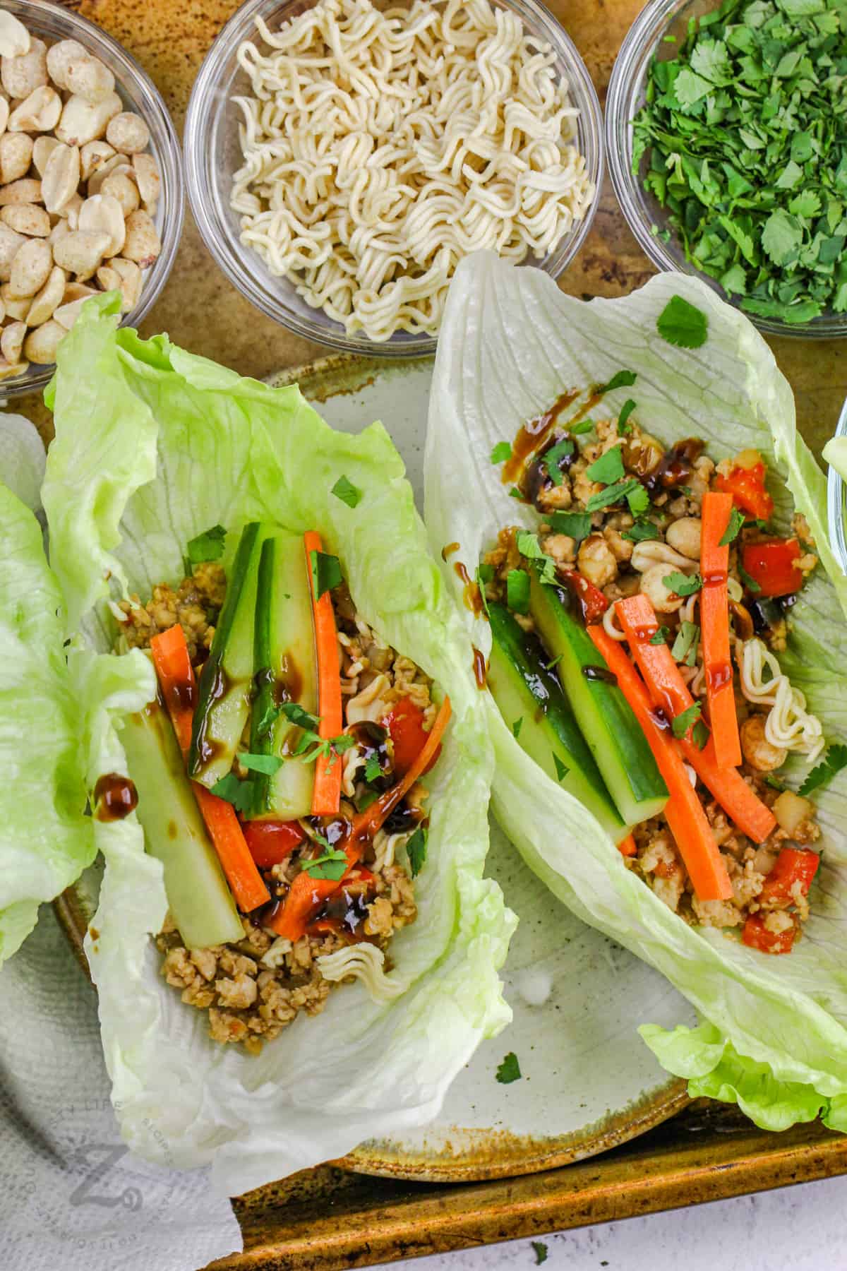 Chicken Lettuce Wraps on a plate with ingredients in bowls