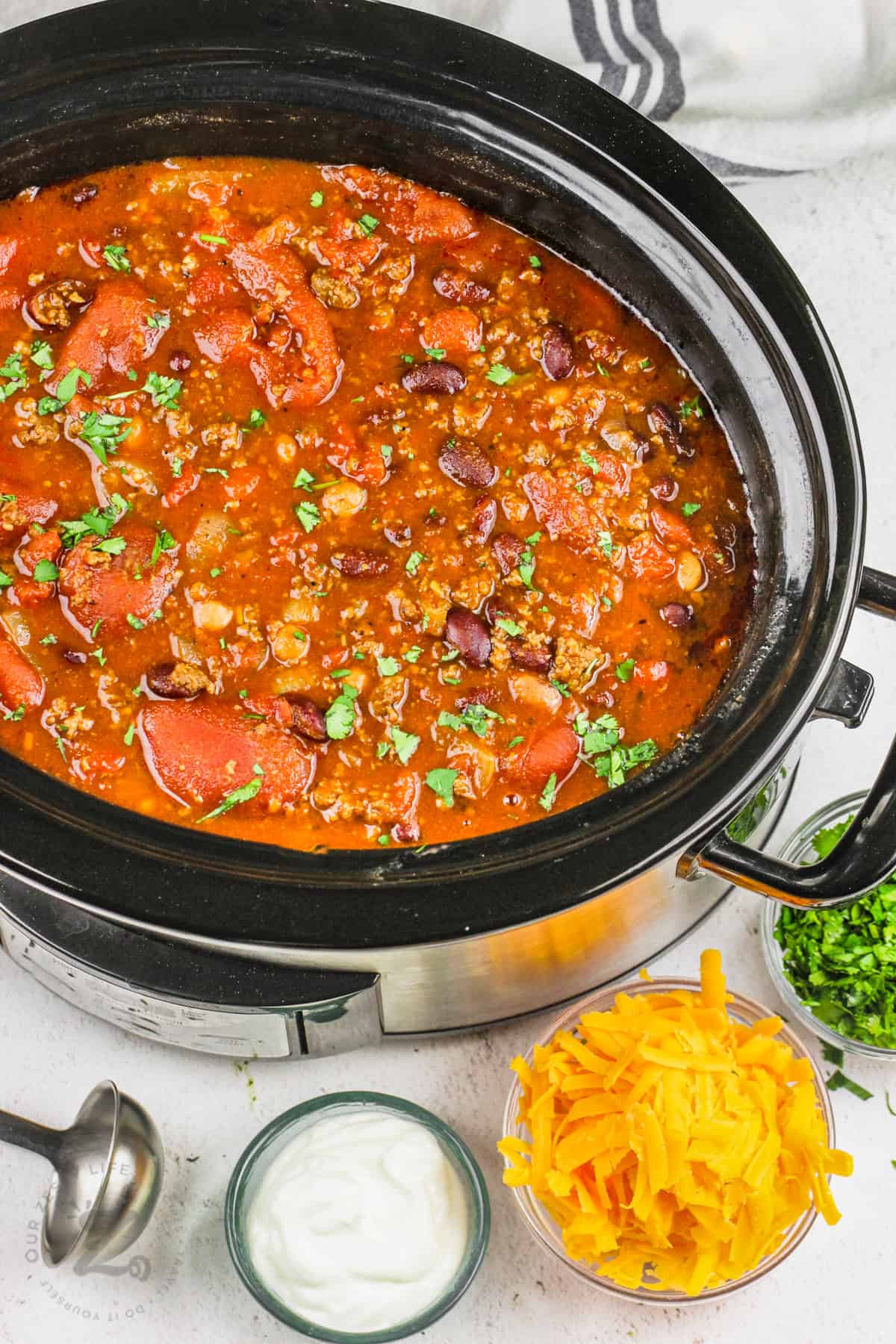 Crockpot Chili Slow Cooker Chili cooked in the pot with ingredients to garnish in bowls