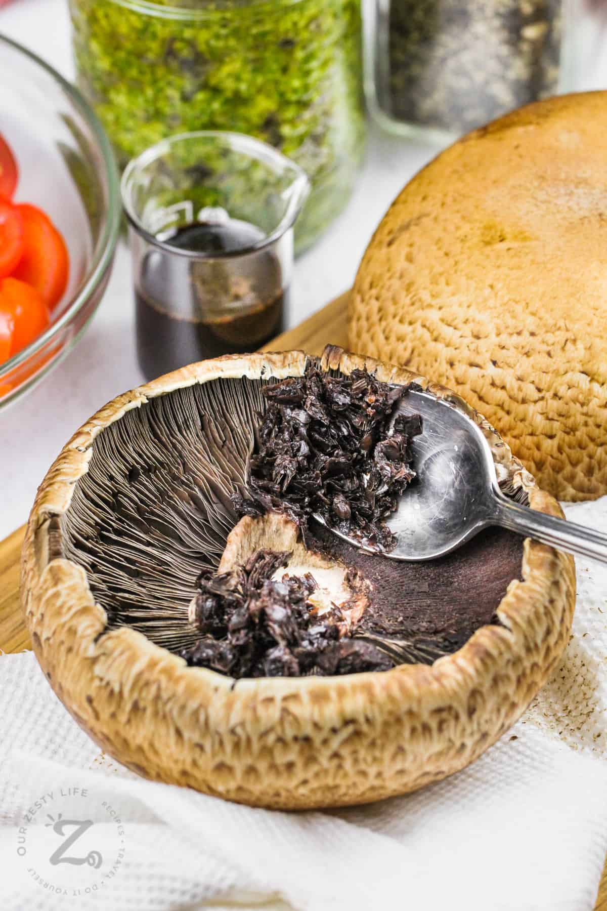 scooping inside out of mushrooms to make Caprese Stuffed Portobello Mushrooms