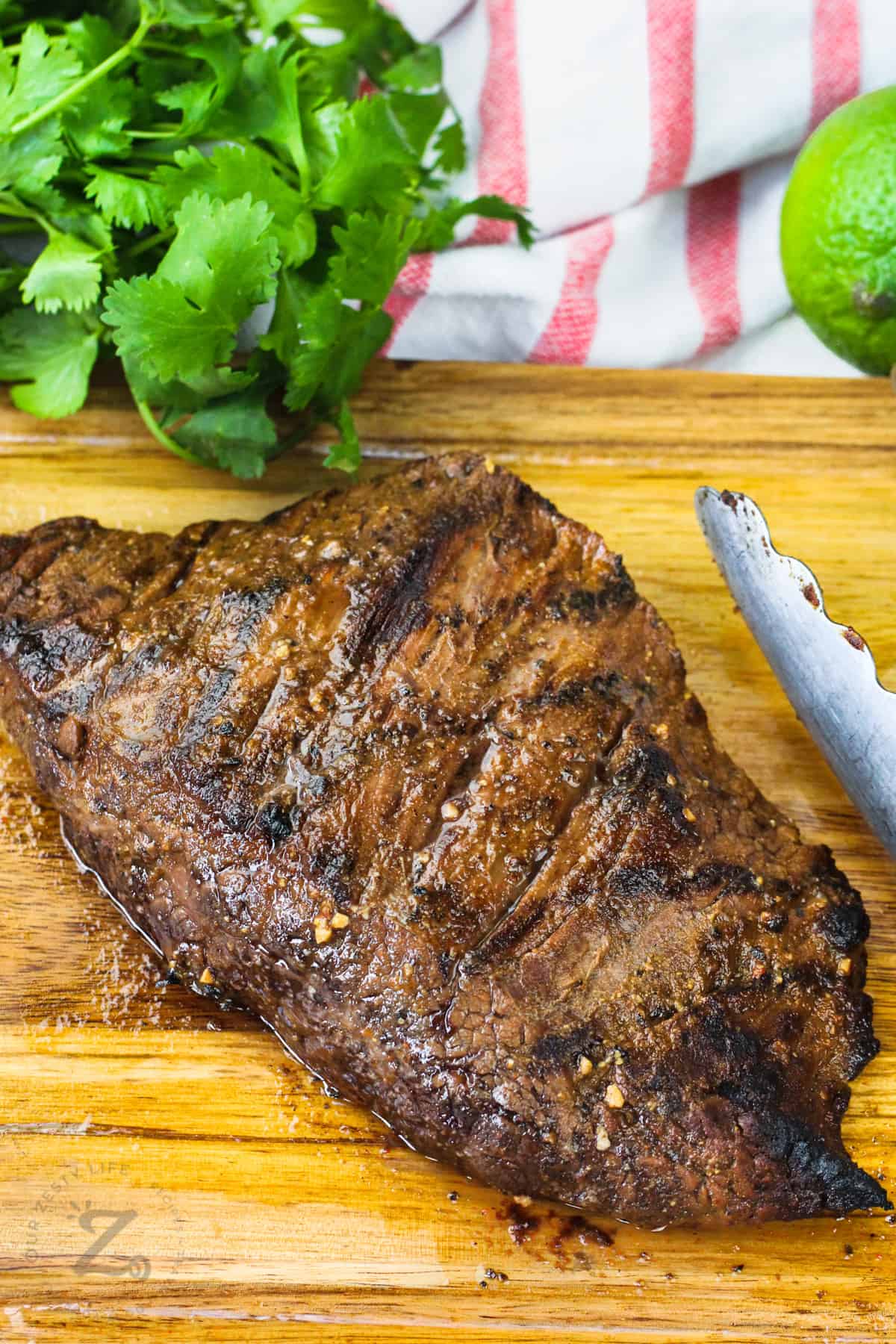 grilled flank steak resting on a wooden board