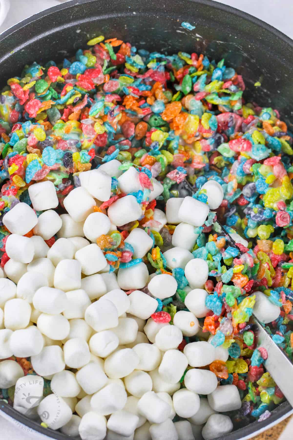 mixing ingredients in pot to make Fruity Pebbles Marshmallow Treats