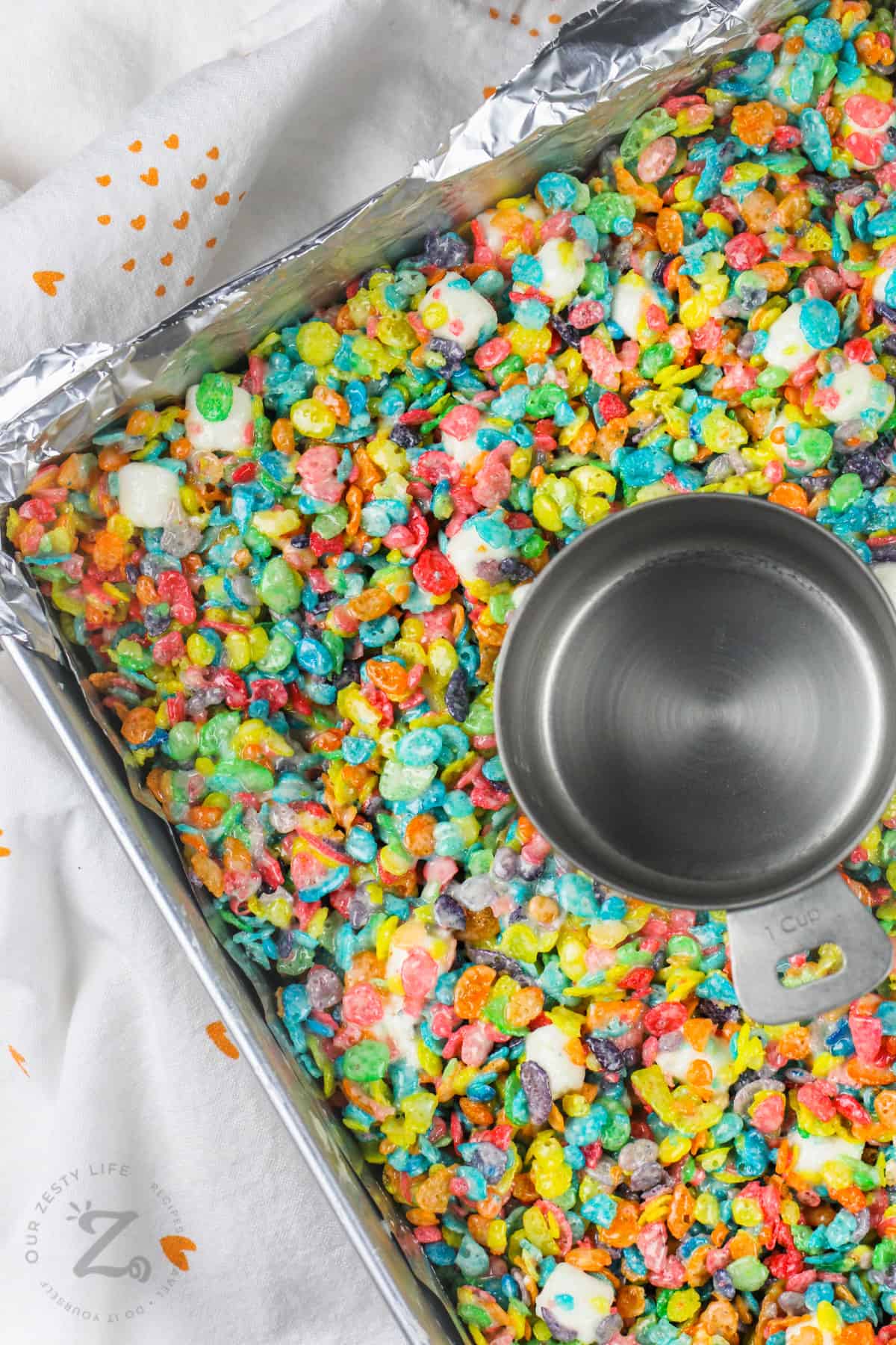 packing down Fruity Pebbles Marshmallow Treats in a dish