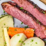 corned beef on a white plate with cabbage, carrots, parsnips and potatoes