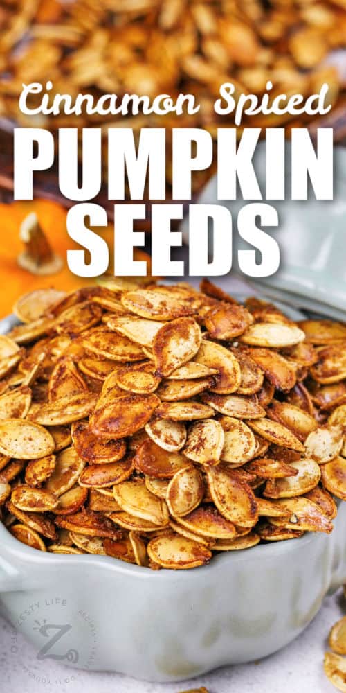 Pumpkin Spice Pumpkin Seeds in a bowl and cooked on a sheet pan with a title