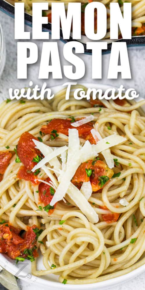 lemon tomato pasta in a white bowl with shredded parmesan and parsley as garnish on top, with writing