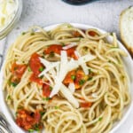 simple lemon tomato pasta in a white bowl with shredded parmesan and parsley as garnish on top