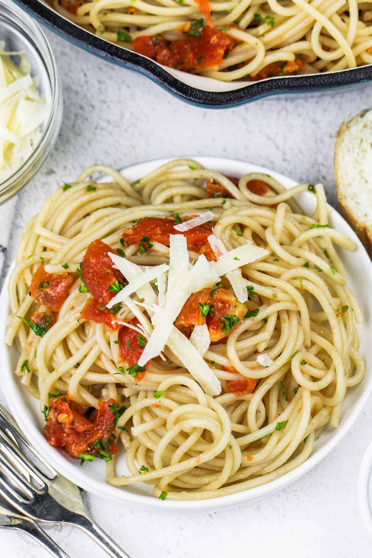 simple lemon tomato pasta in a white bowl with shredded parmesan and parsley as garnish on top
