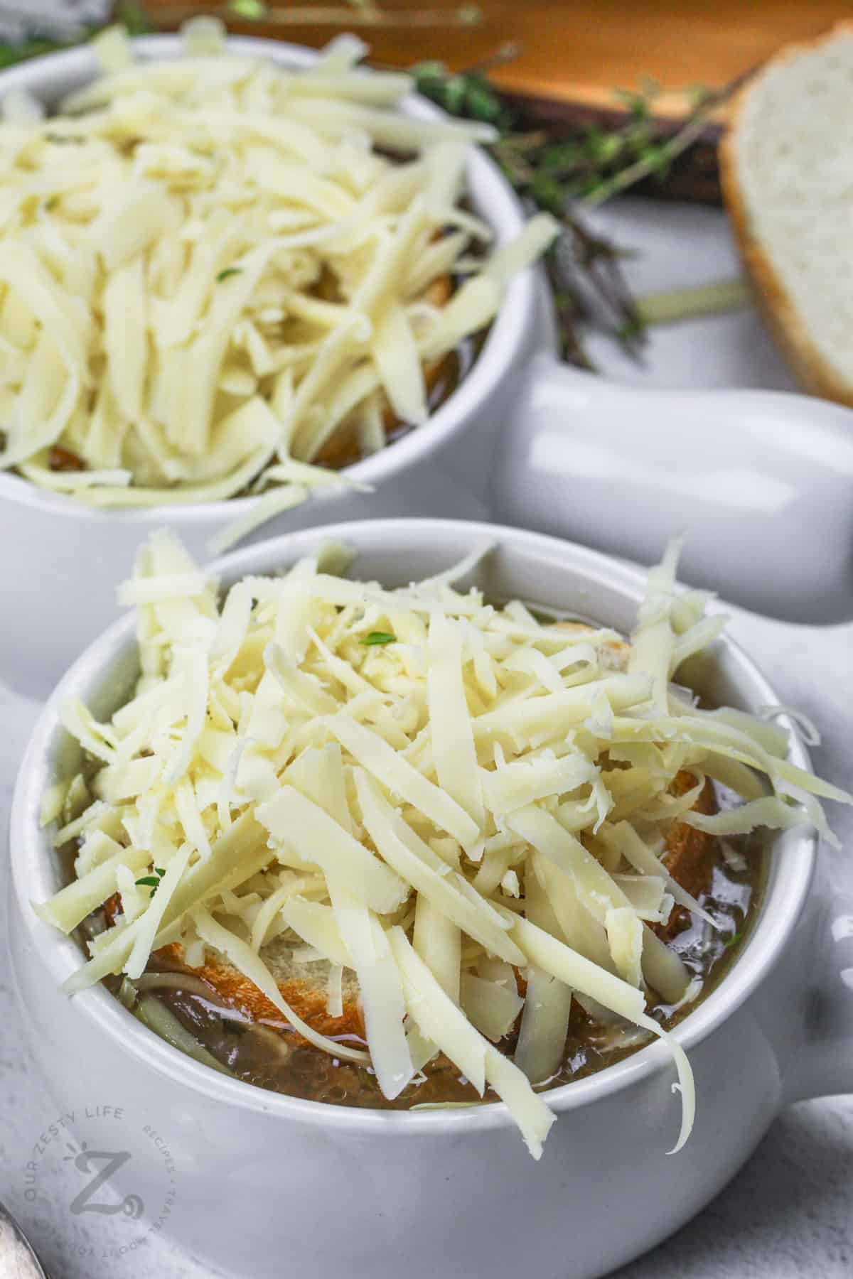 adding cheese on top of Crockpot French Onion Soup