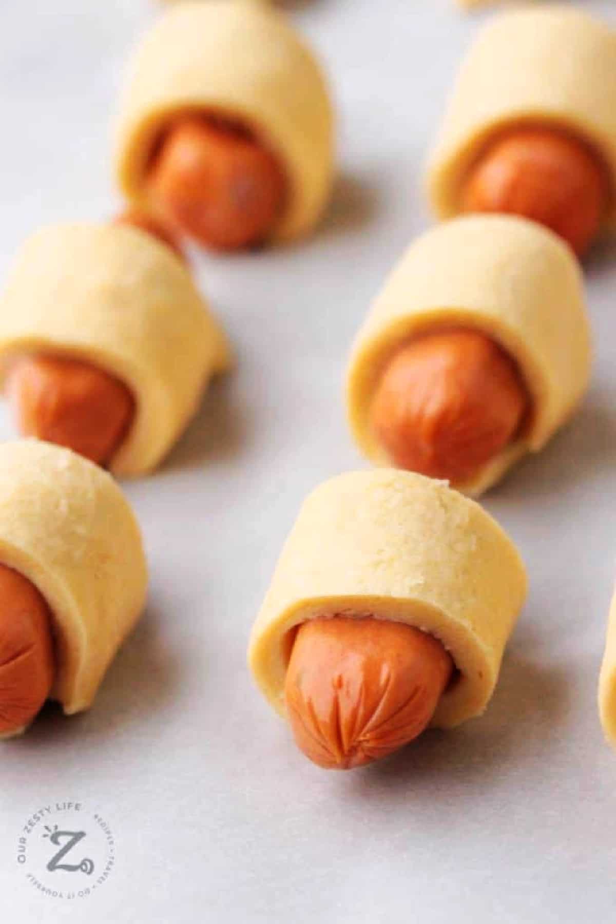 uncooked mini pigs in a blanket on a baking sheet