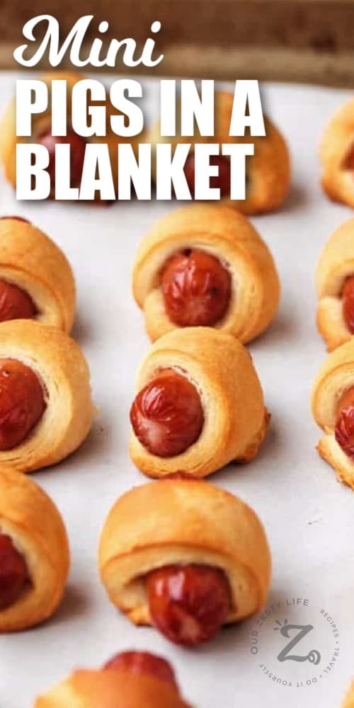 cooked mini pigs in a blanket on a baking sheet with a title