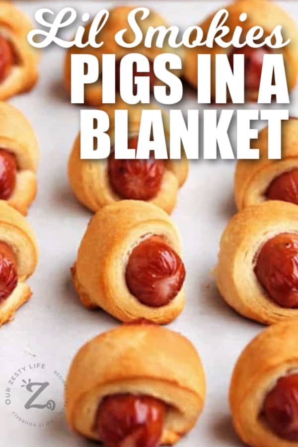 cooked mini pigs in a blanket on a parchment lined baking sheet, with writing
