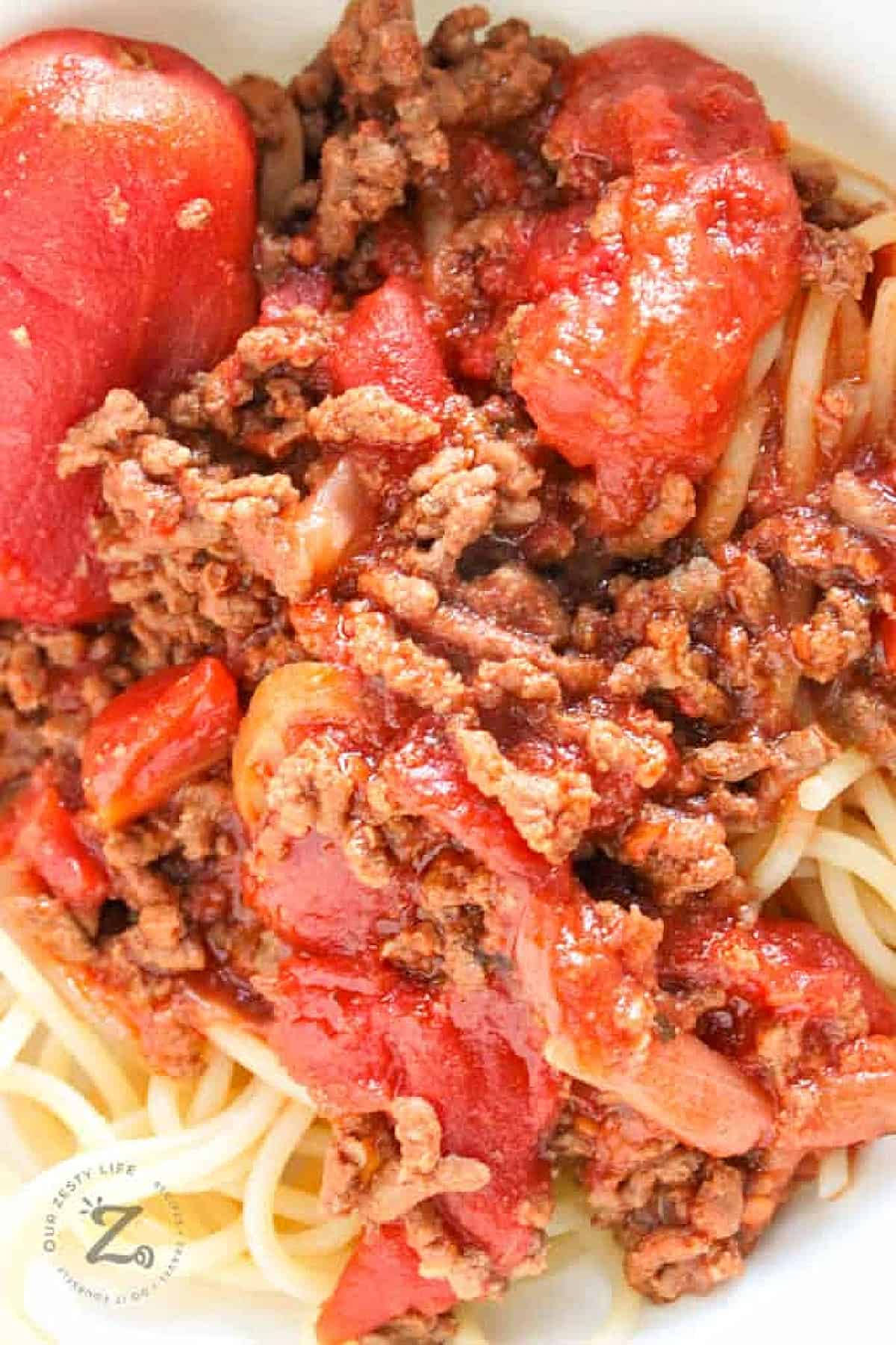 slow cooker spaghetti sauce, served over spaghetti, in a white bowl