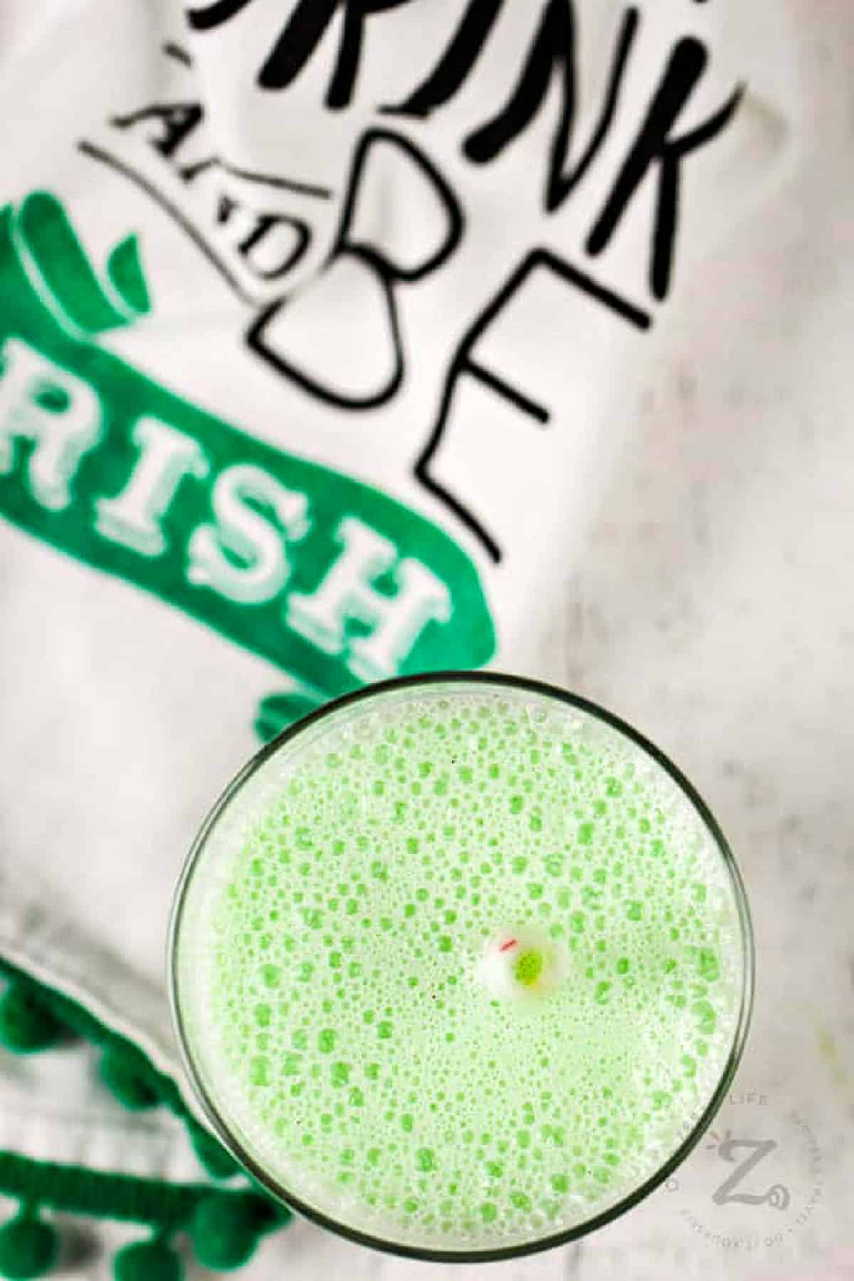 copycat shamrock shake in a clear glass with a straw and a towel beside it