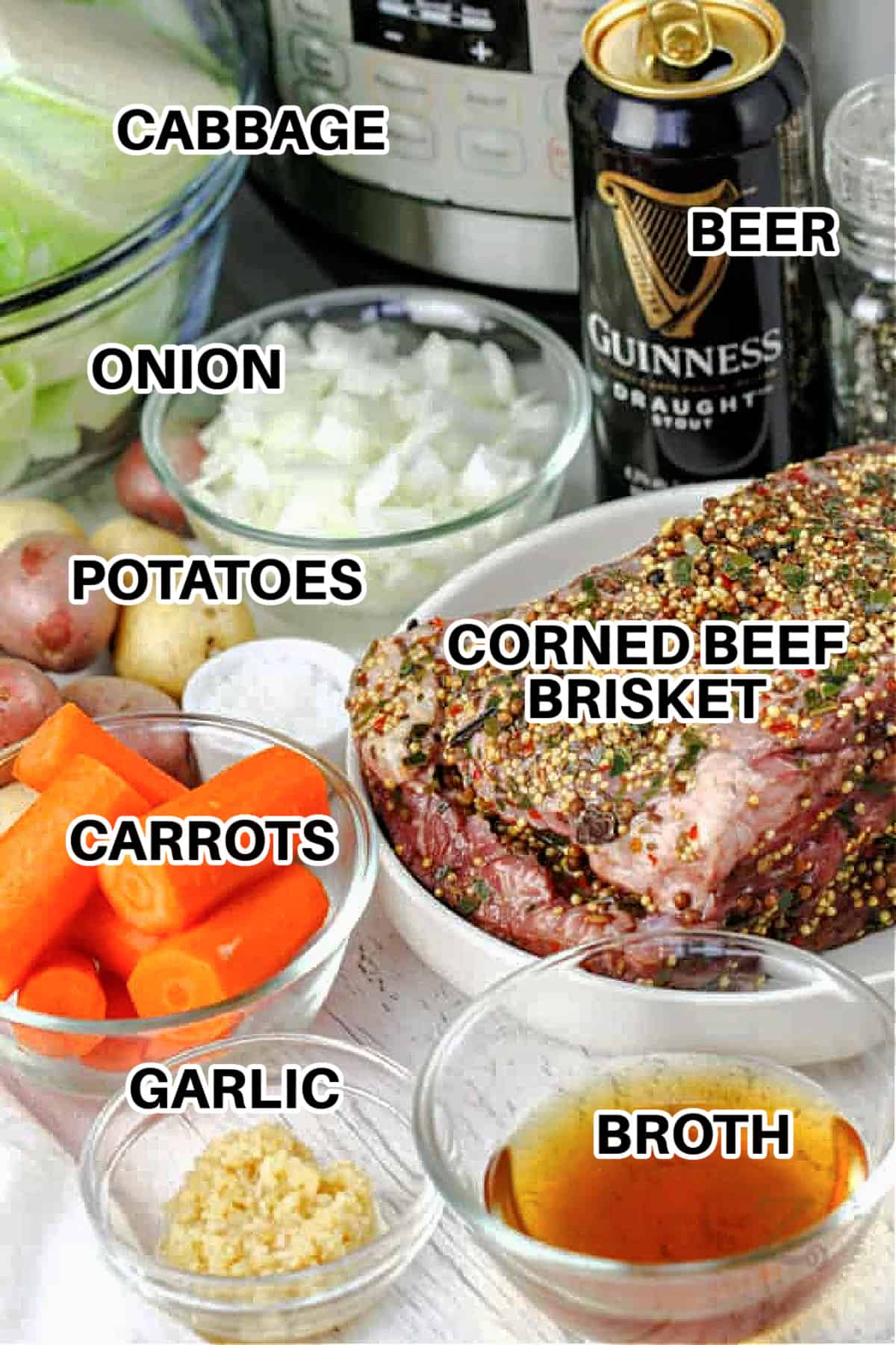 labeled ingredients such as corned beef brisket, beer, broth, minced garlic, carrots, potatoes, cabbage and onions assembled to make Instant Pot corned beef and cabbage recipe