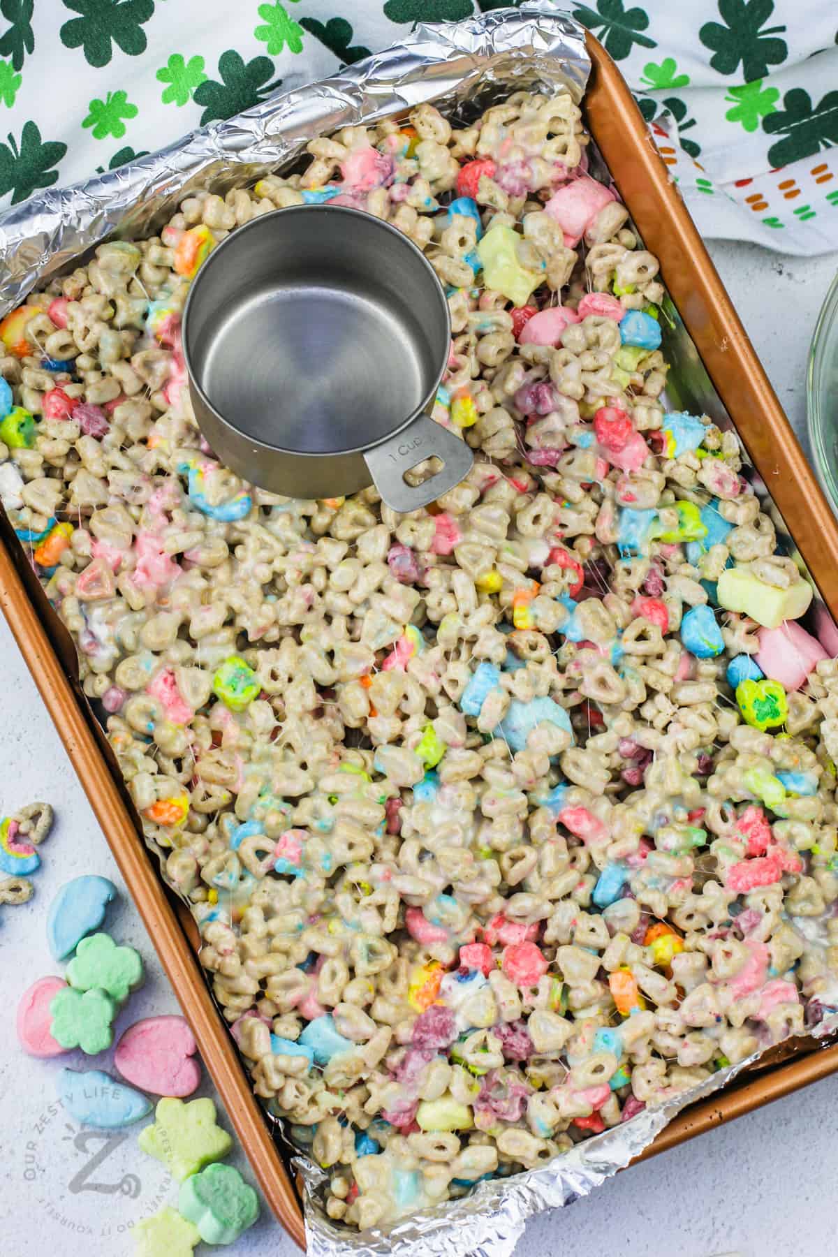adding Lucky Charms Marshmallow Treats Squares ingredients to the pan