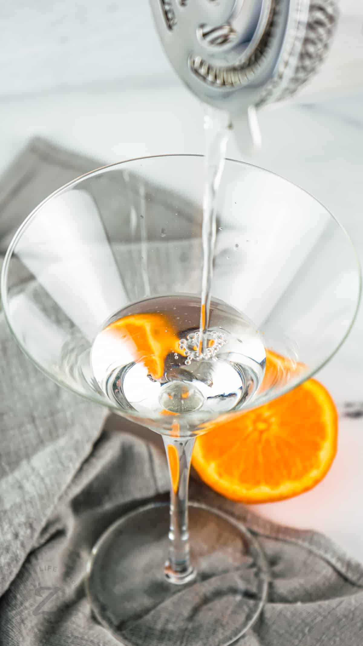 adding mixed liquids to martini glass to make Traditional Gin Martini