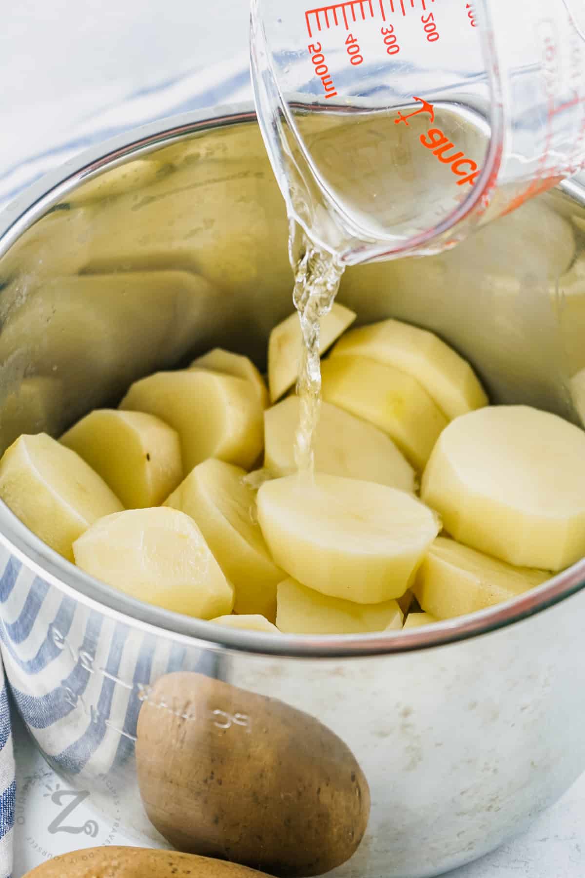 pouring water on potatoes to make Instant Pot Mashed Potatoes