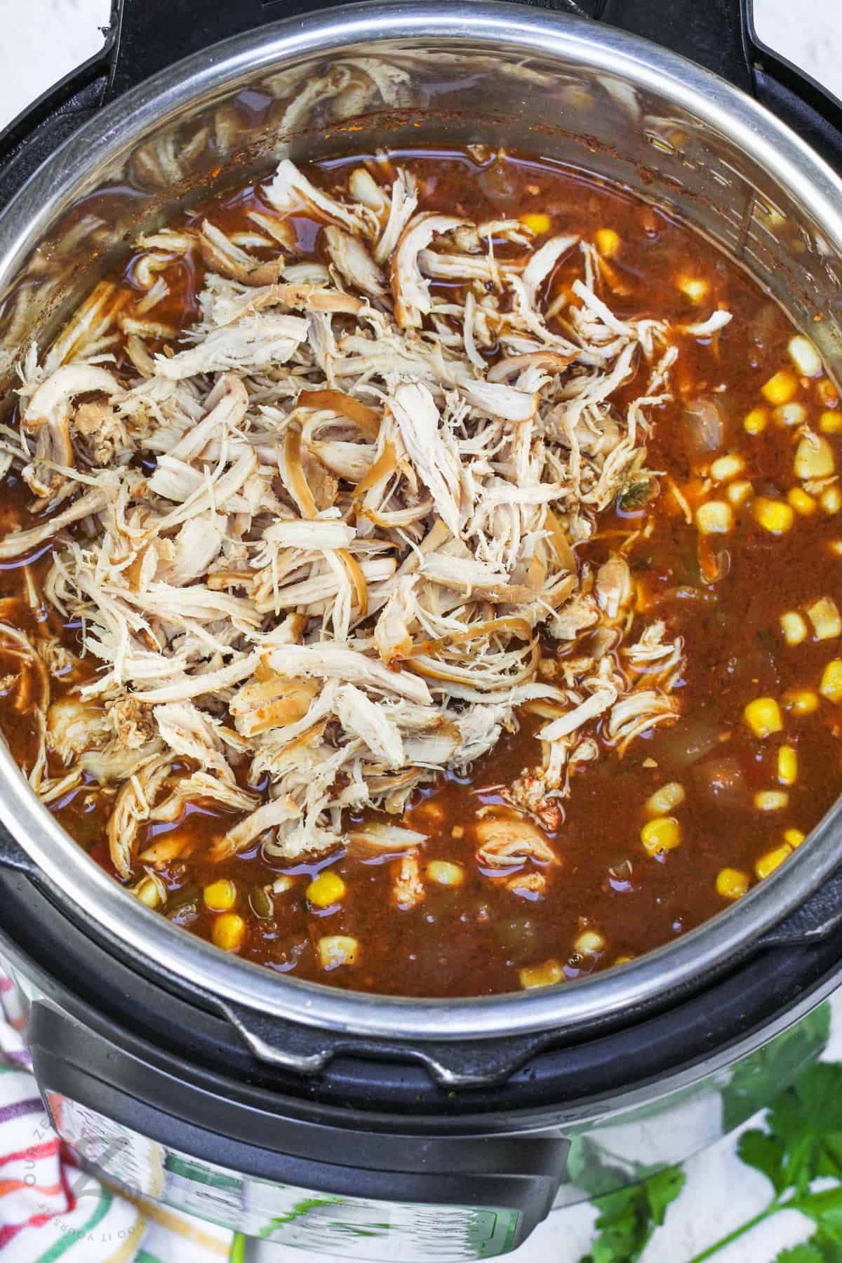 adding chicken to pot to make Instant Pot Tortilla Chicken Soup