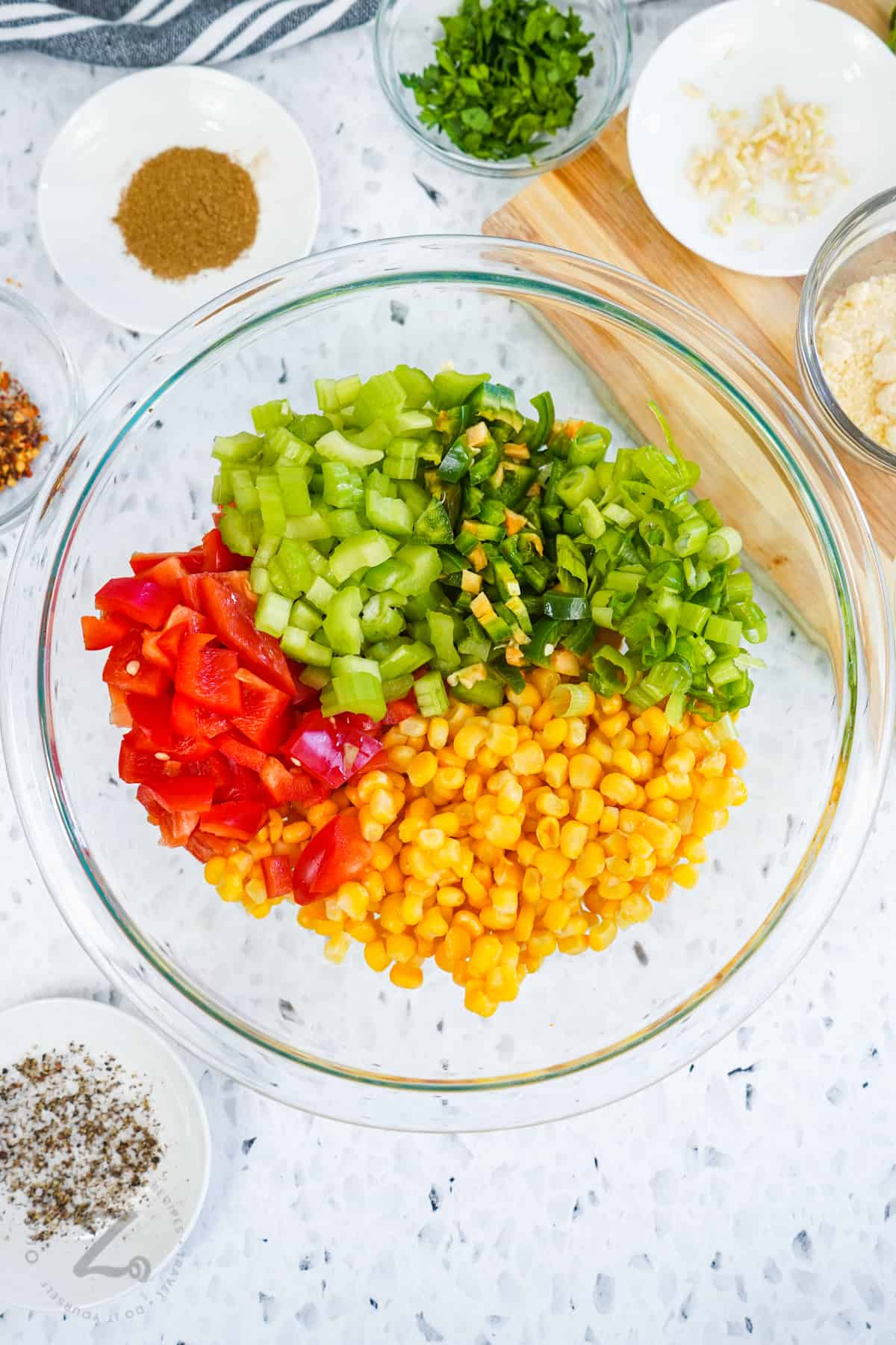 ingredients in a bowl to make Corn Salad with seasonings in bowls beside it