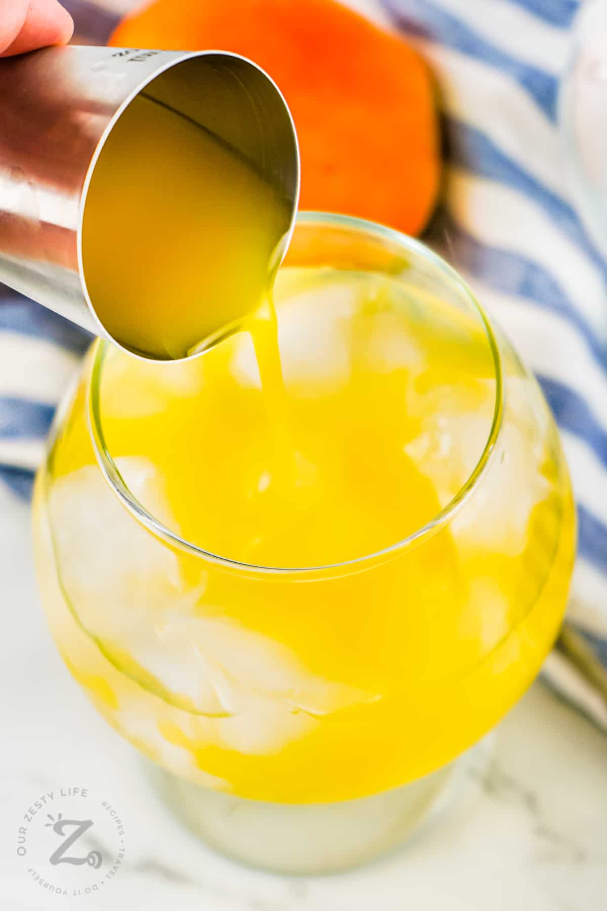 adding orange juice to glass to make Sex on the Beach Cocktail