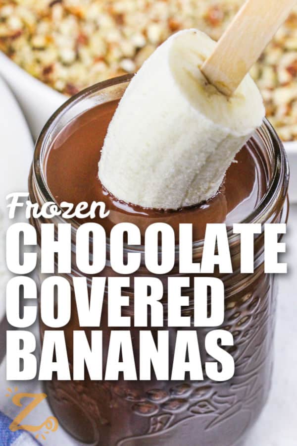 dipping a banana on a stick in chocolate to make Frozen Chocolate Covered Bananas