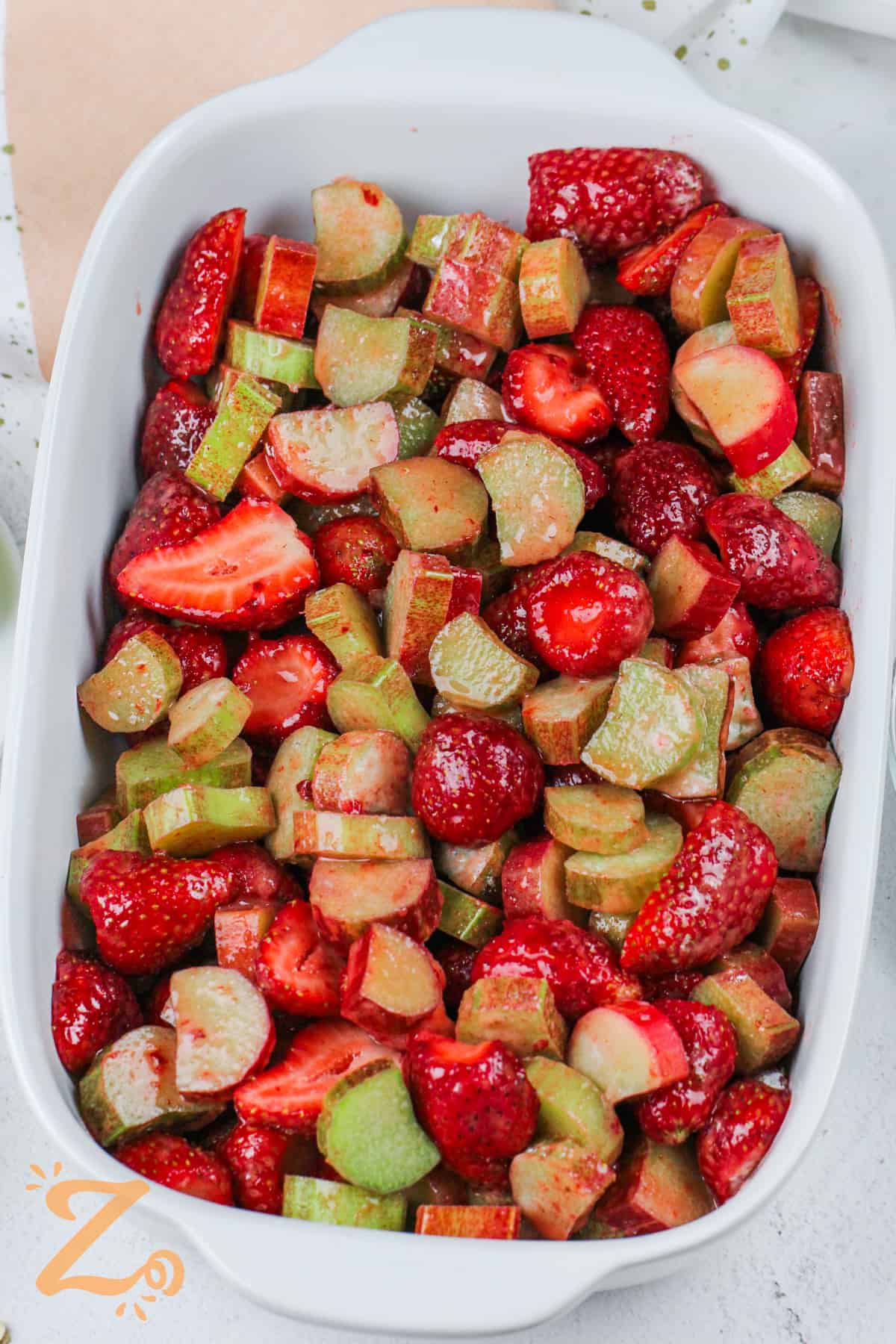 adding strawberry and rhubarb to the dish to make Strawberry Rhubarb Crisp