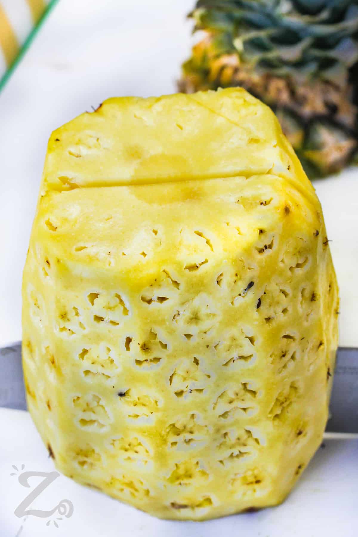 slicing a pineapple in half to make Grilled Pineapple