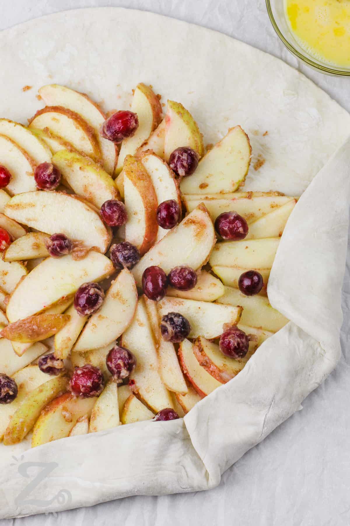 folding pastry over apple filling to make Apple Galette