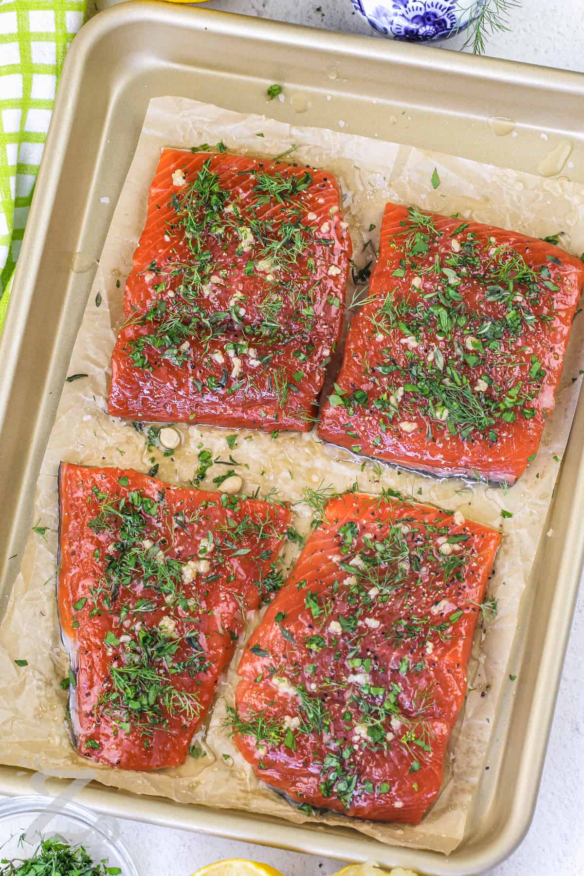 salmon fillets on a baking sheet topped with herbs