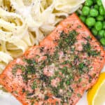 baked salmon being served on a plate with pasta and peas