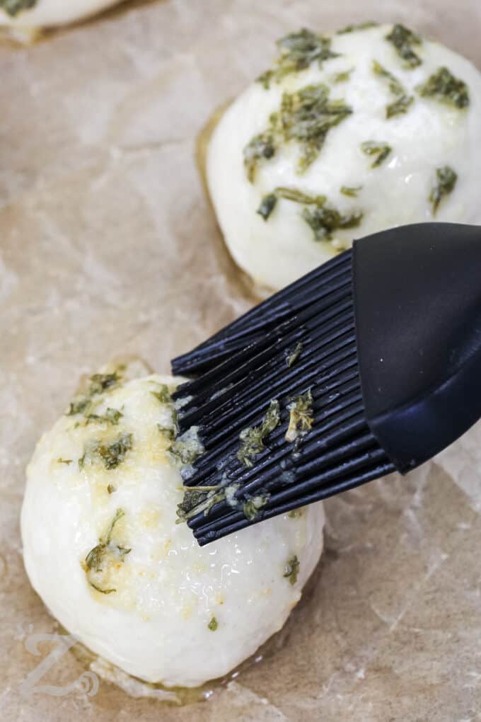 Garlic cheese bombs being brushed with butter mixture