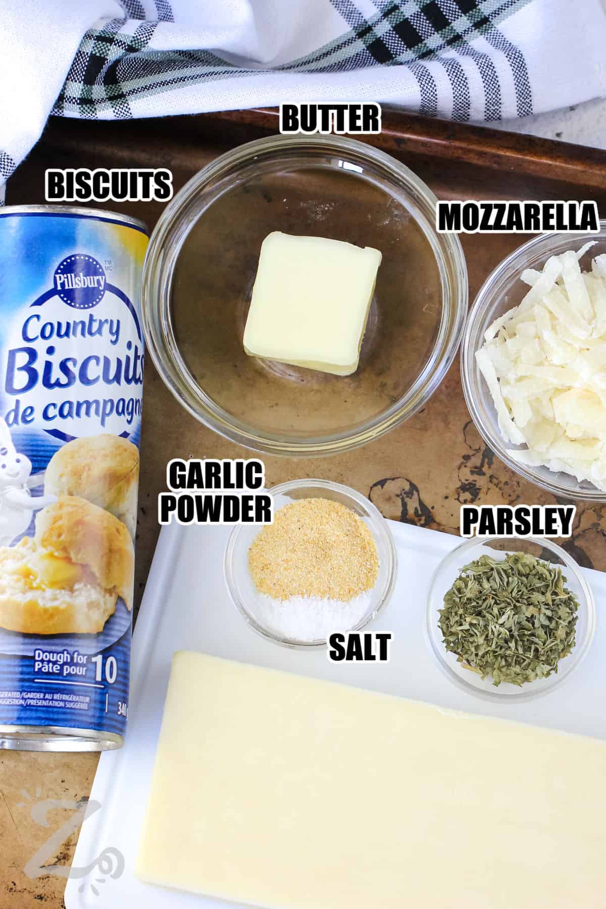 ingredients to make garlic cheese bombs labeled on a baking tray