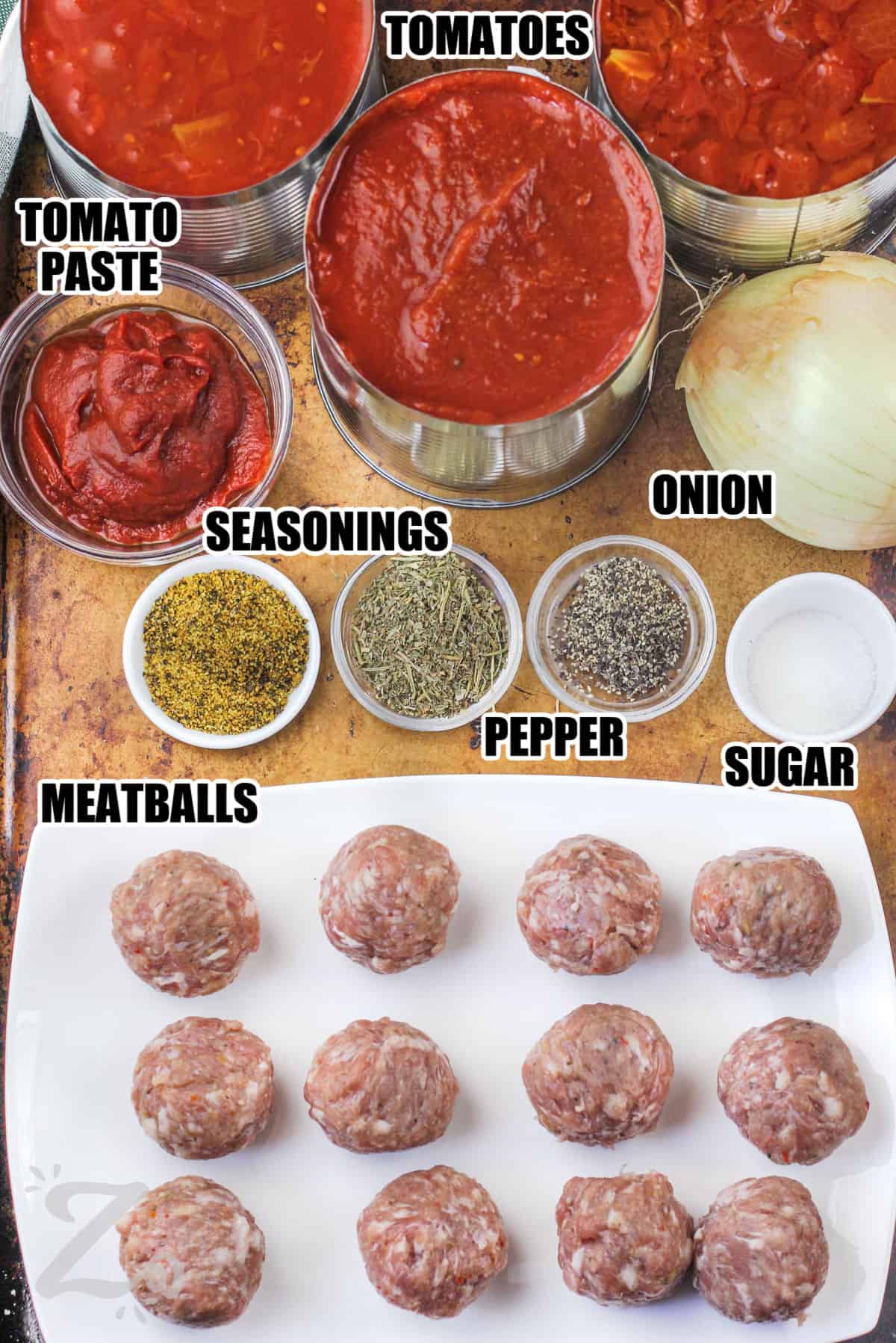 Labeled ingredients to make meatball sauce with prepared meatballs on a tray
