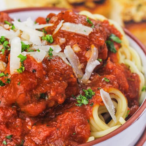 a bowl of meatballs with sauce over spaghetti