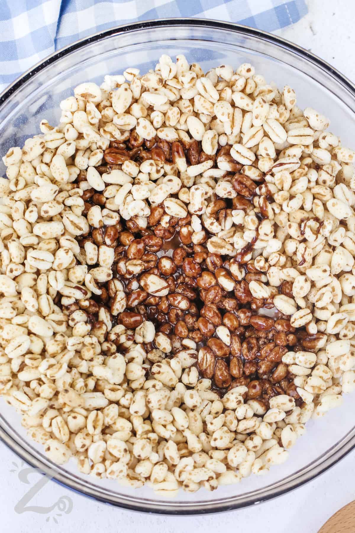 puffed wheat and the puffed wheat sauce being combined in a bowl