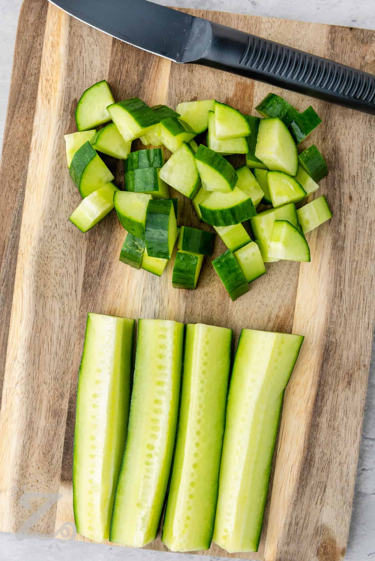cucumber being chopped on a cutting board